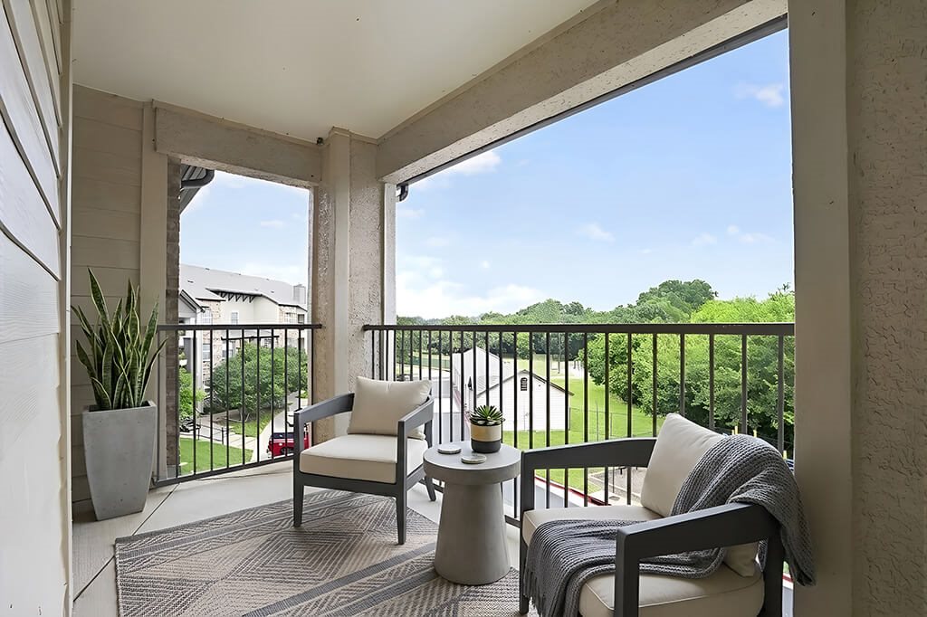 A balcony with a chair, a table, and a potted plant.